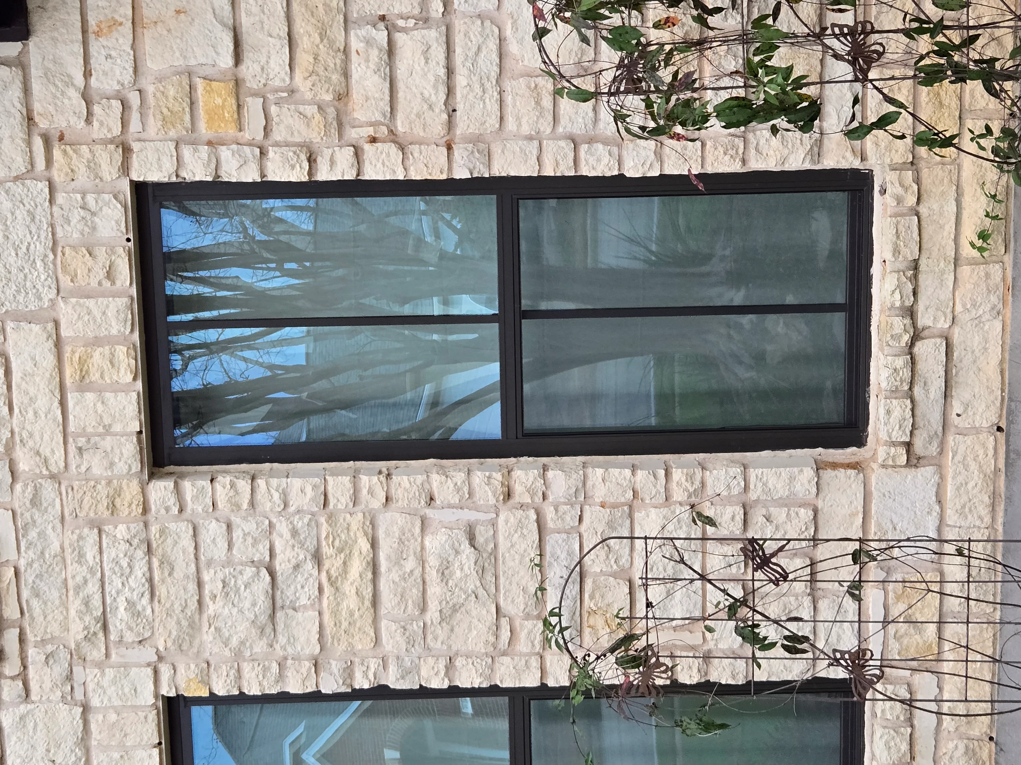 Black-framed modern windows installed in cream stone wall with horizontal muntins