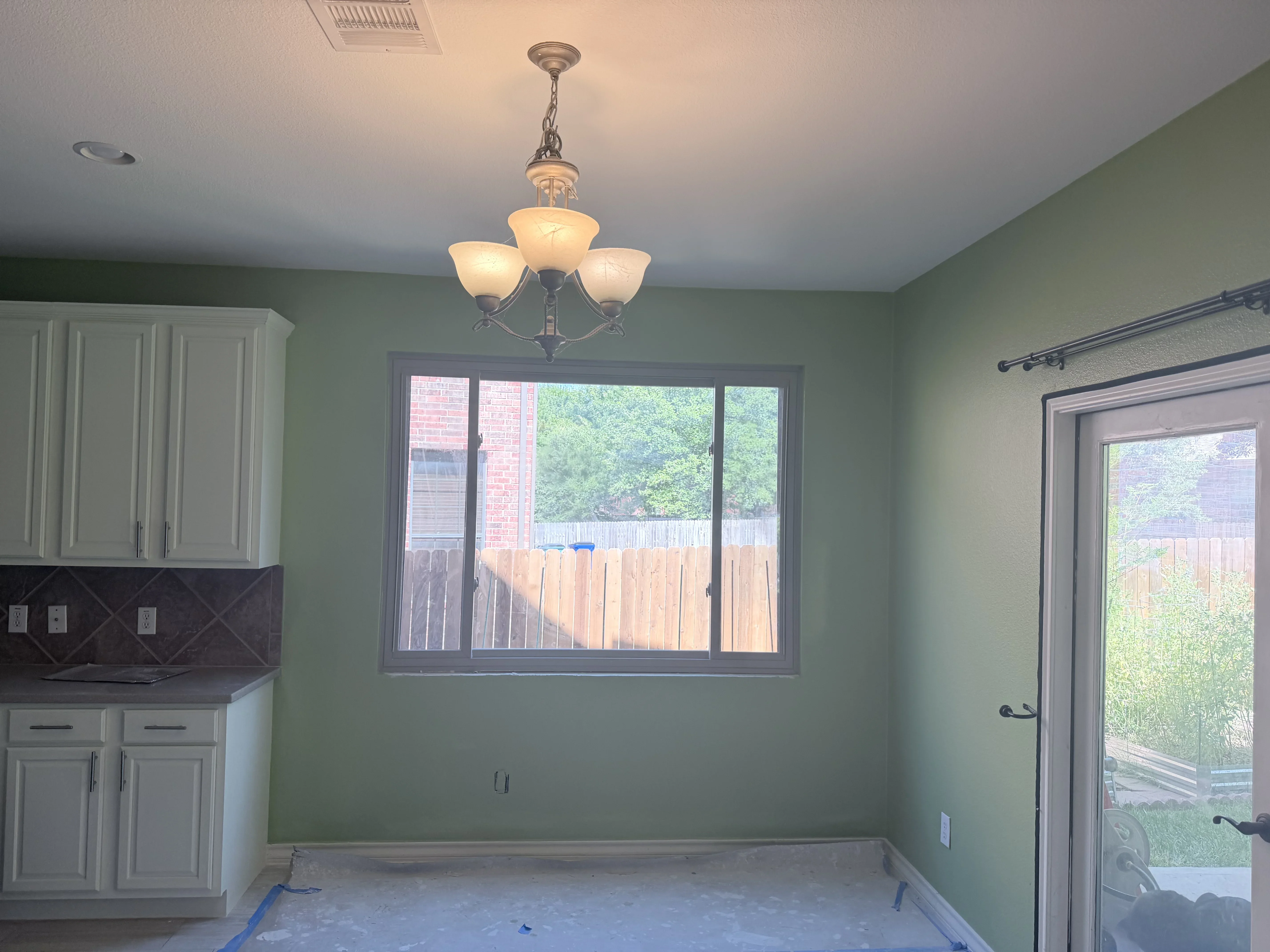 Installed sliding glass door and window with dark frames in kitchen with sage green walls