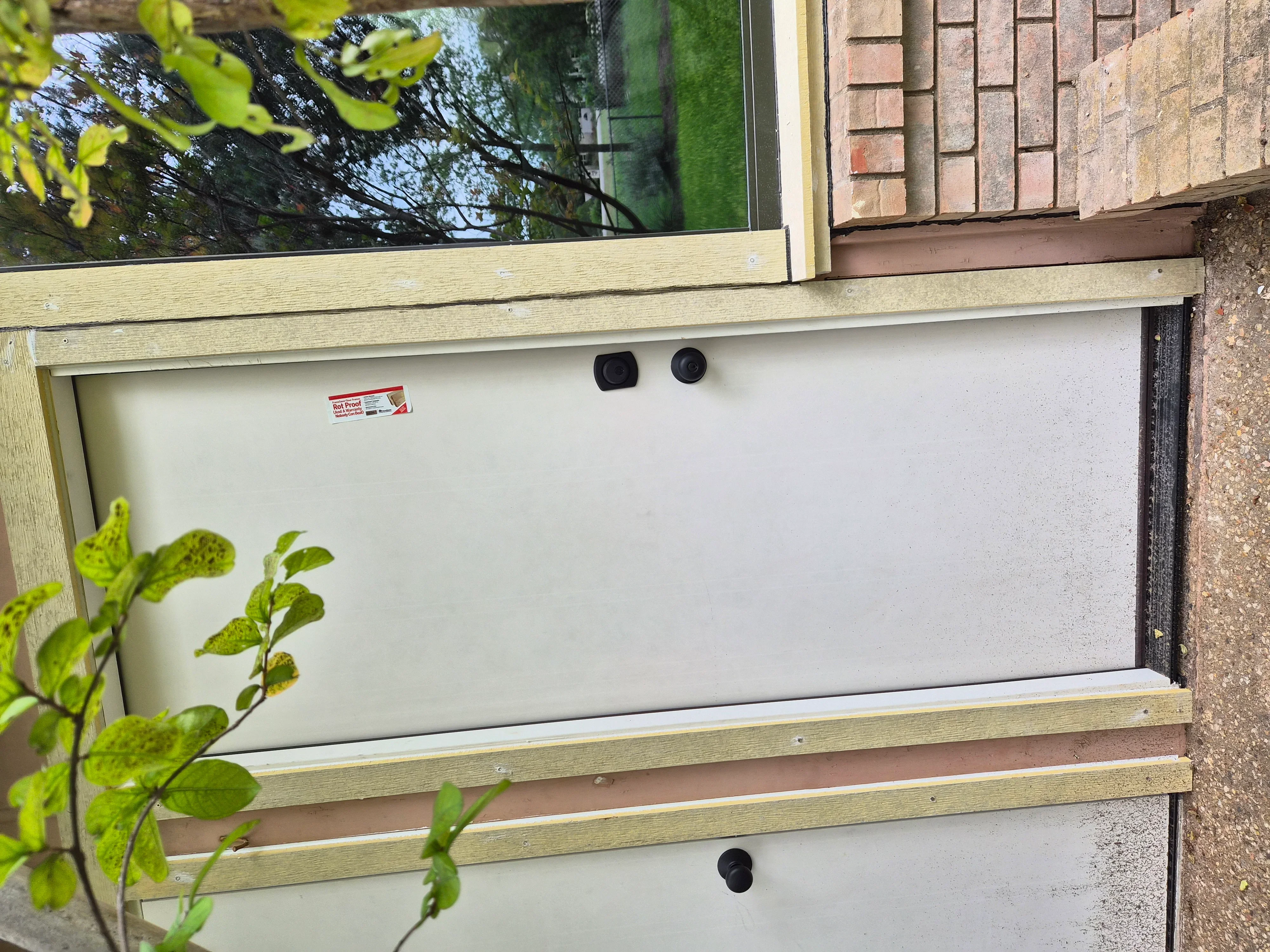 Newly installed energy-efficient window with white frame and wood trim on brick home exterior