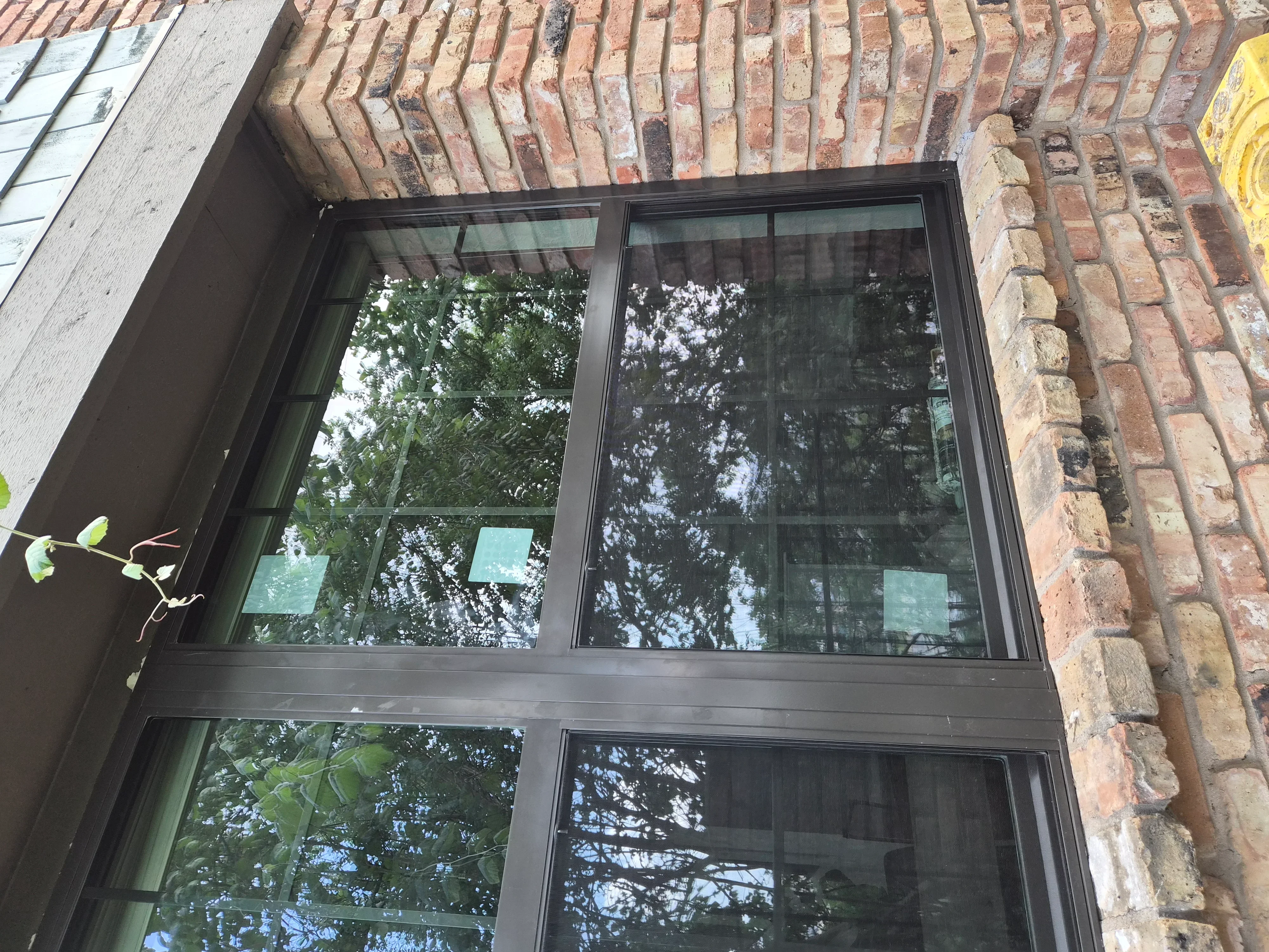Black-framed four-pane window installed in red brick wall with herringbone pattern