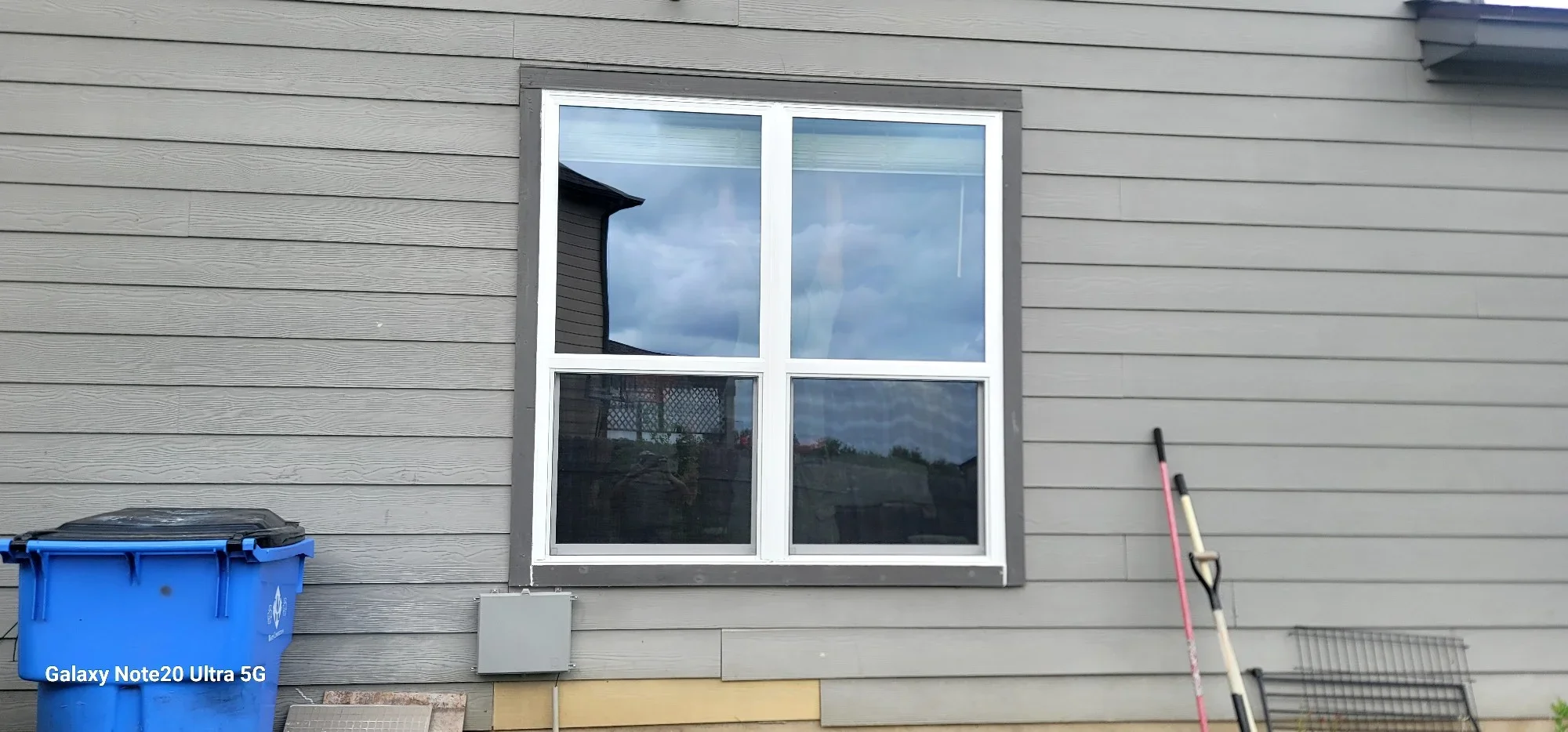 Four-pane white window installed on gray horizontal siding with gray trim