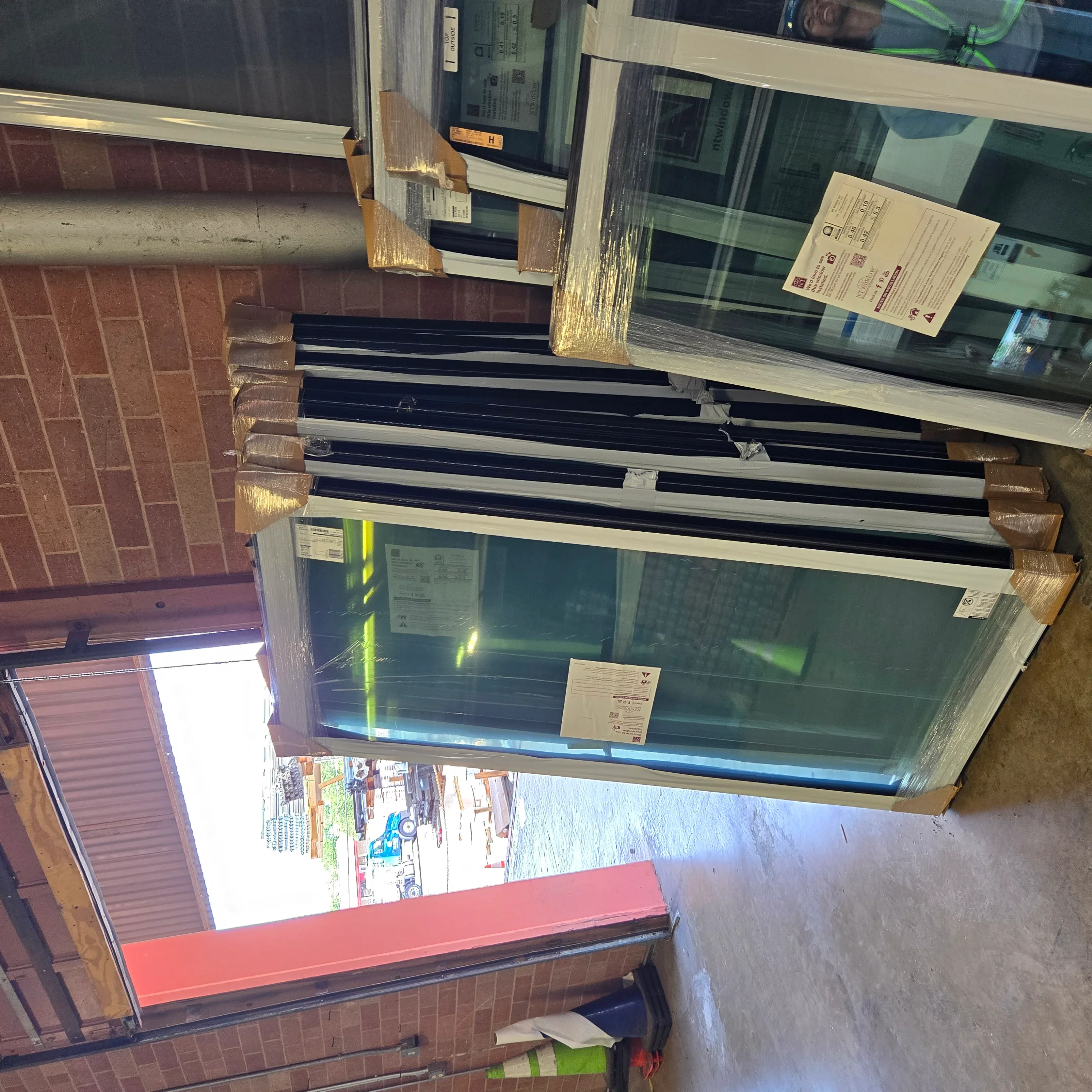 Multiple energy-efficient windows with black frames installed in brick opening during installation process