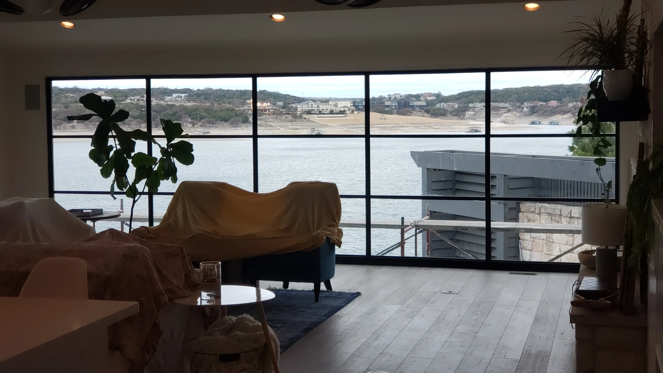 Five-panel black-framed picture windows overlooking water and hillside landscape